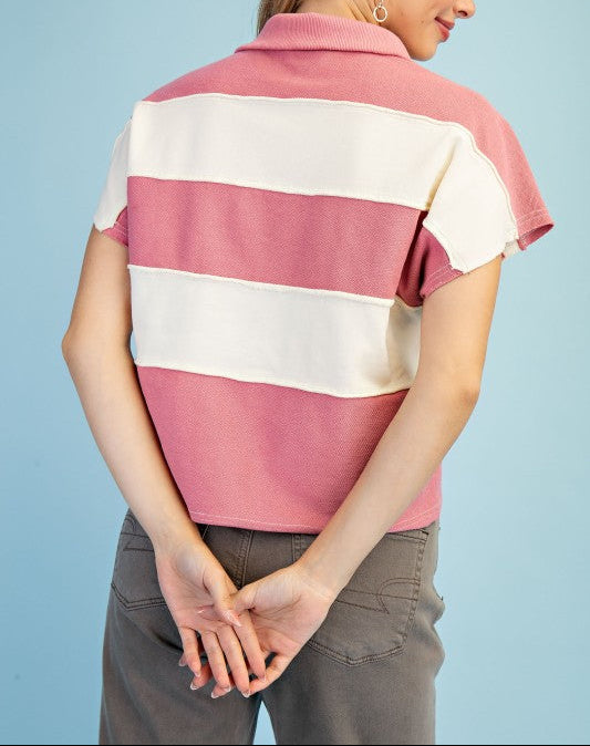 Woman wearing a pink and white striped polo shirt against a light blue background
