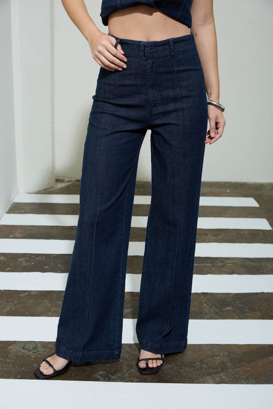 Person wearing dark blue wide-leg pants standing on a striped floor.