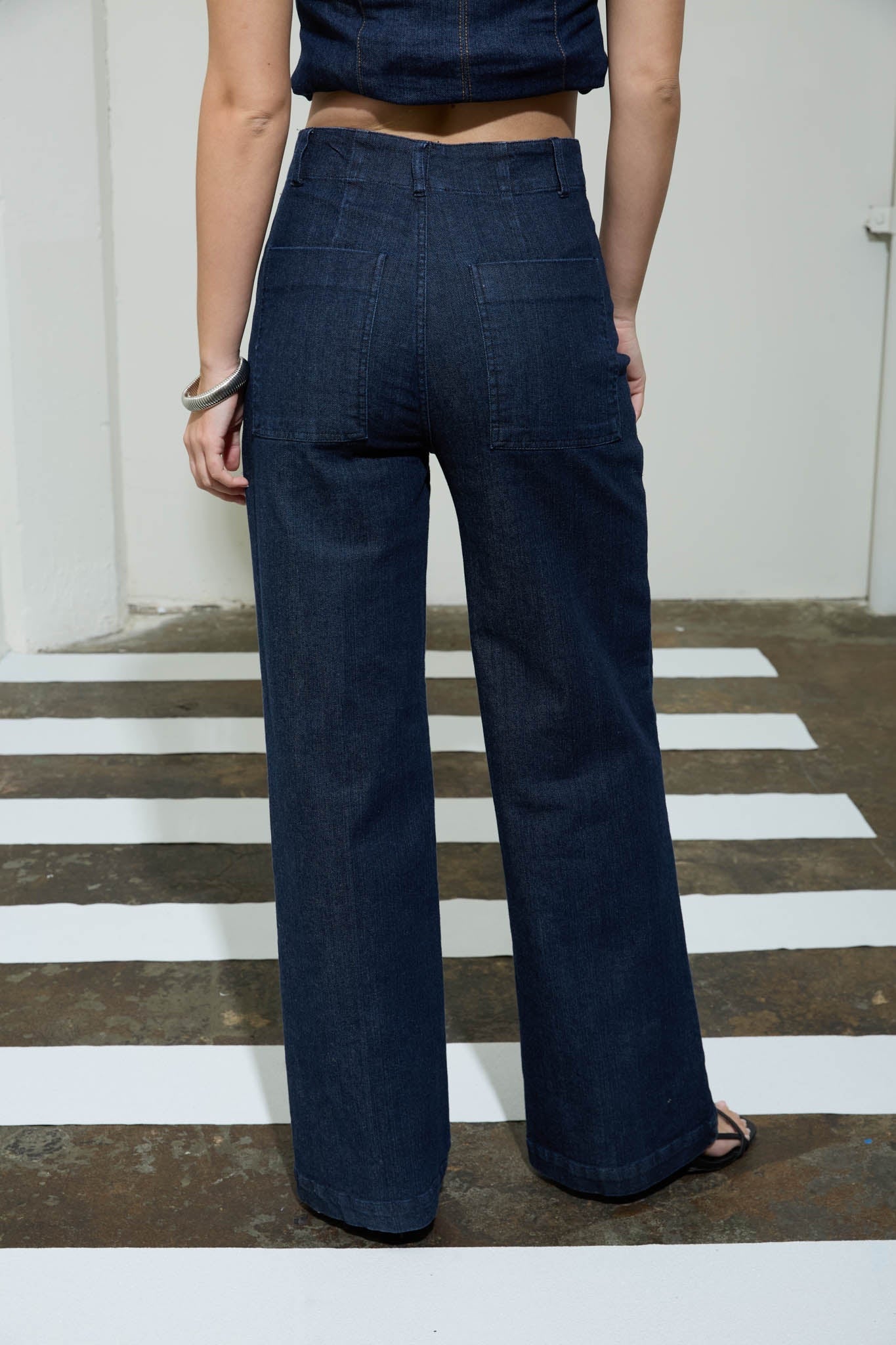 Person wearing dark blue wide-leg pants standing on a striped floor.