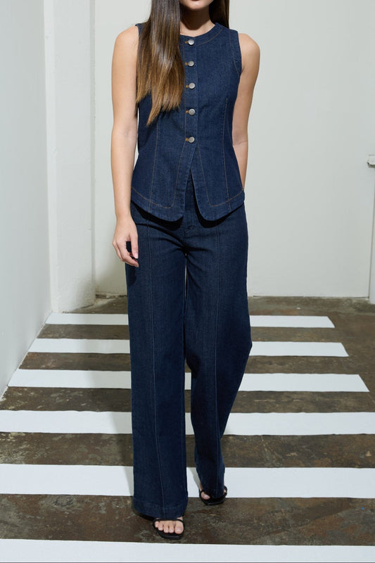 Woman wearing a navy blue sleeveless top and pants standing on a white and gray striped floor.