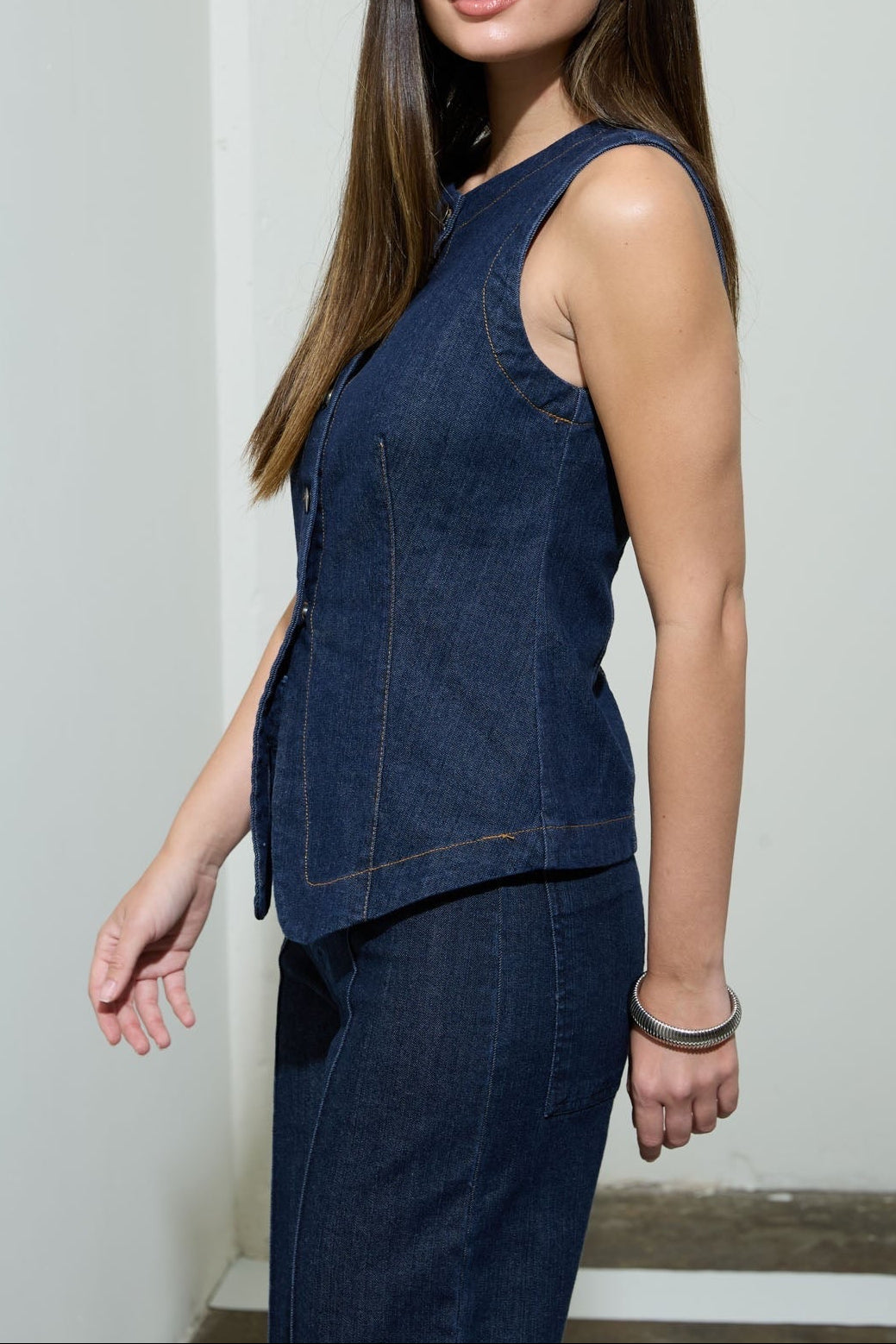 Woman wearing a dark blue sleeveless top and pants against a plain background