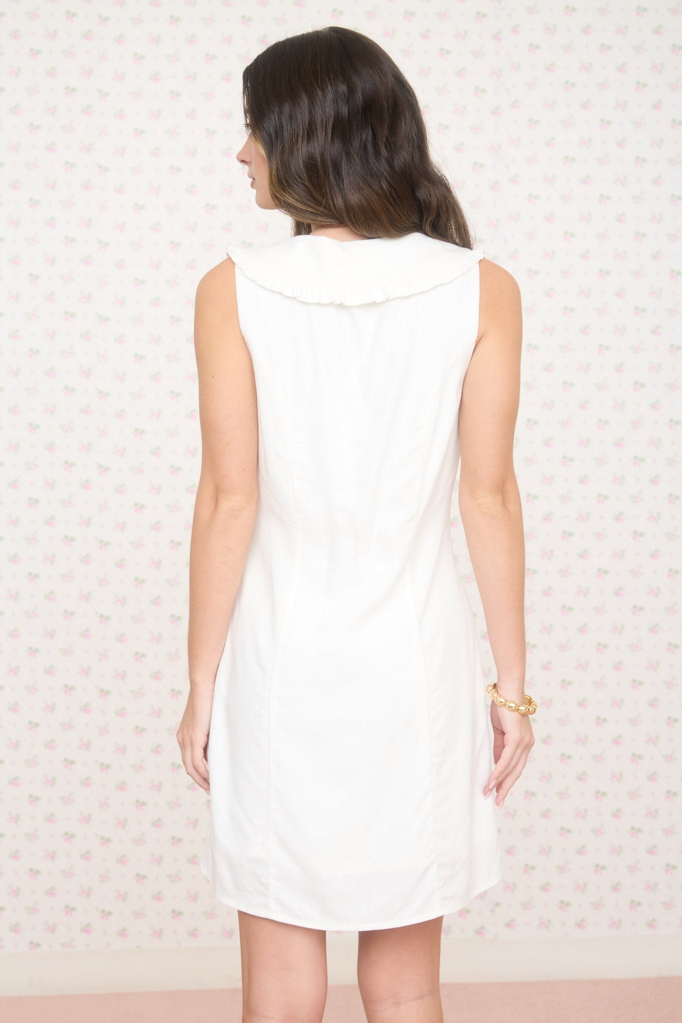 Woman wearing a white sleeveless dress against a light background