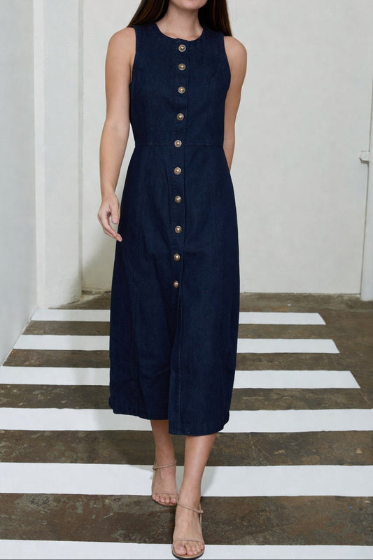 Woman wearing a navy sleeveless dress with buttons on a white and gray striped floor.