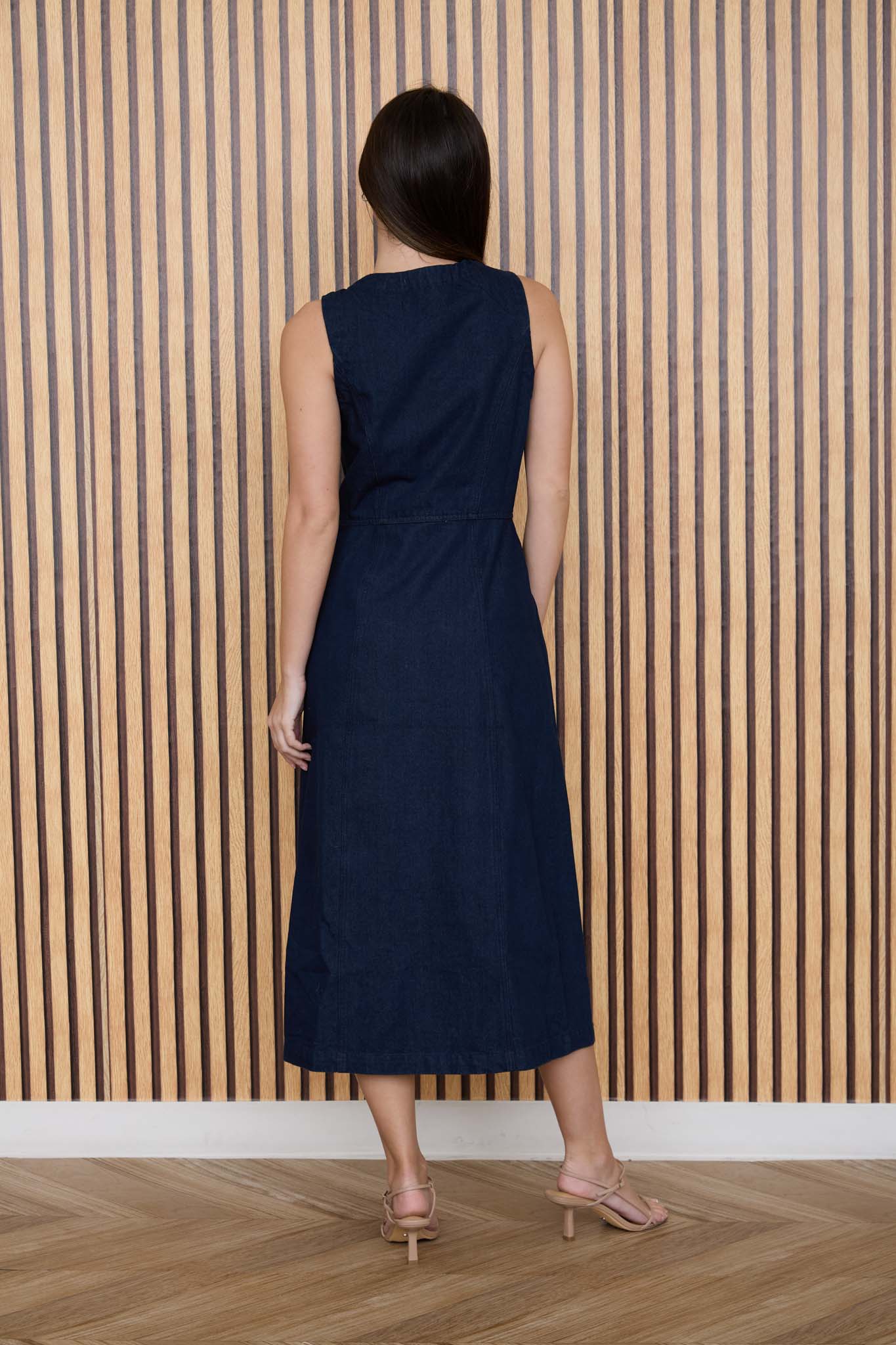 Woman wearing a navy dress standing against a striped wall.