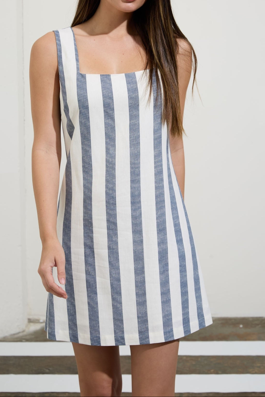 Woman wearing a blue and white striped dress against a plain background