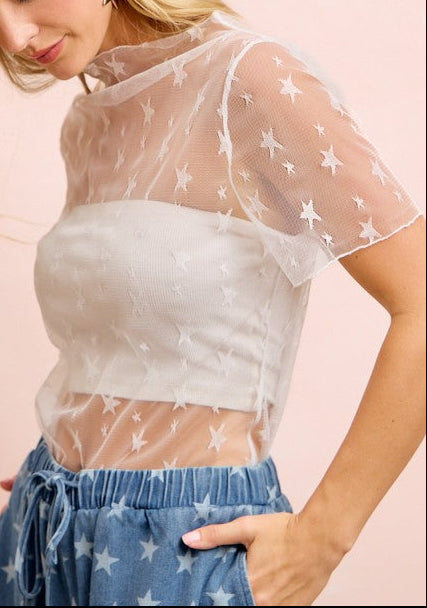 Woman wearing a sheer top with star patterns on a pink background