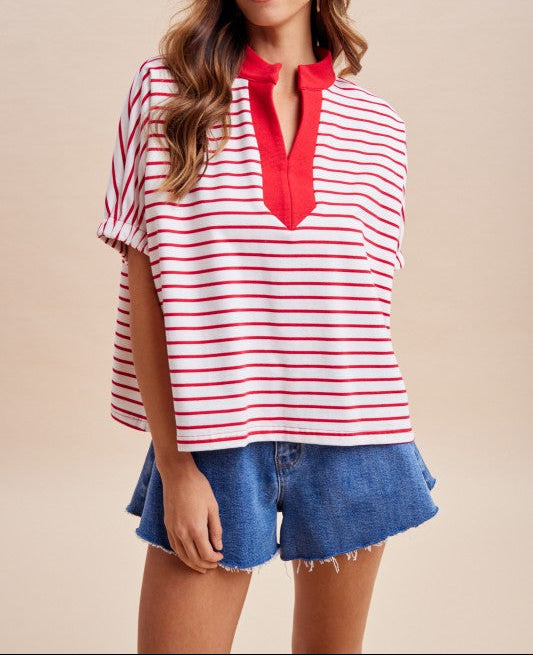 Woman wearing a red and white striped top with a red collar and denim shorts on a beige background