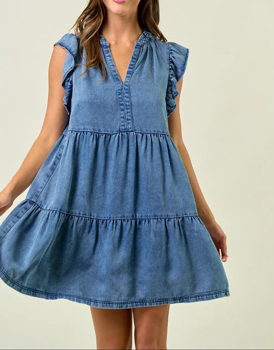 Woman wearing a blue denim dress against a plain background