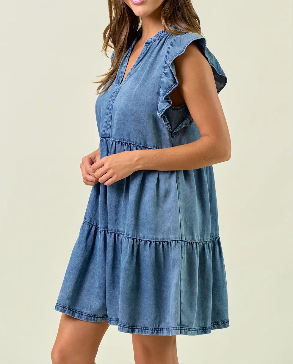 Woman wearing a blue denim dress against a plain background