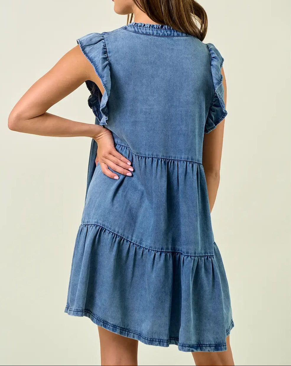 Woman wearing a blue denim dress against a plain background