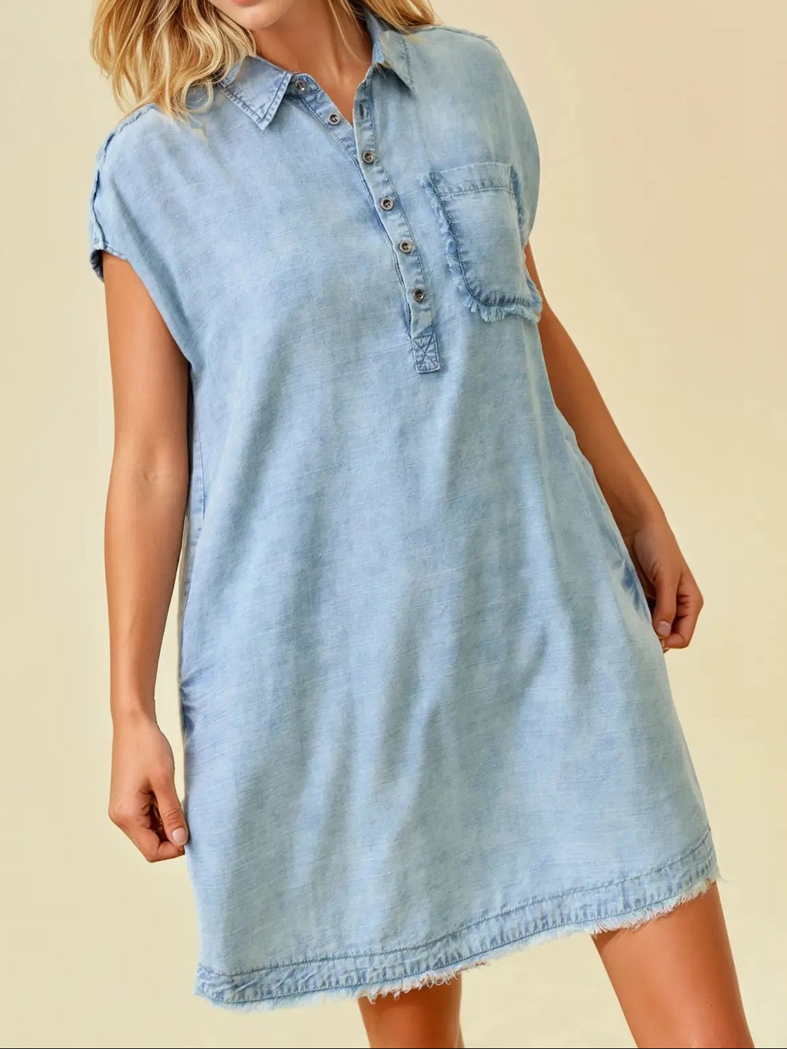 Woman wearing a light blue denim dress against a beige background