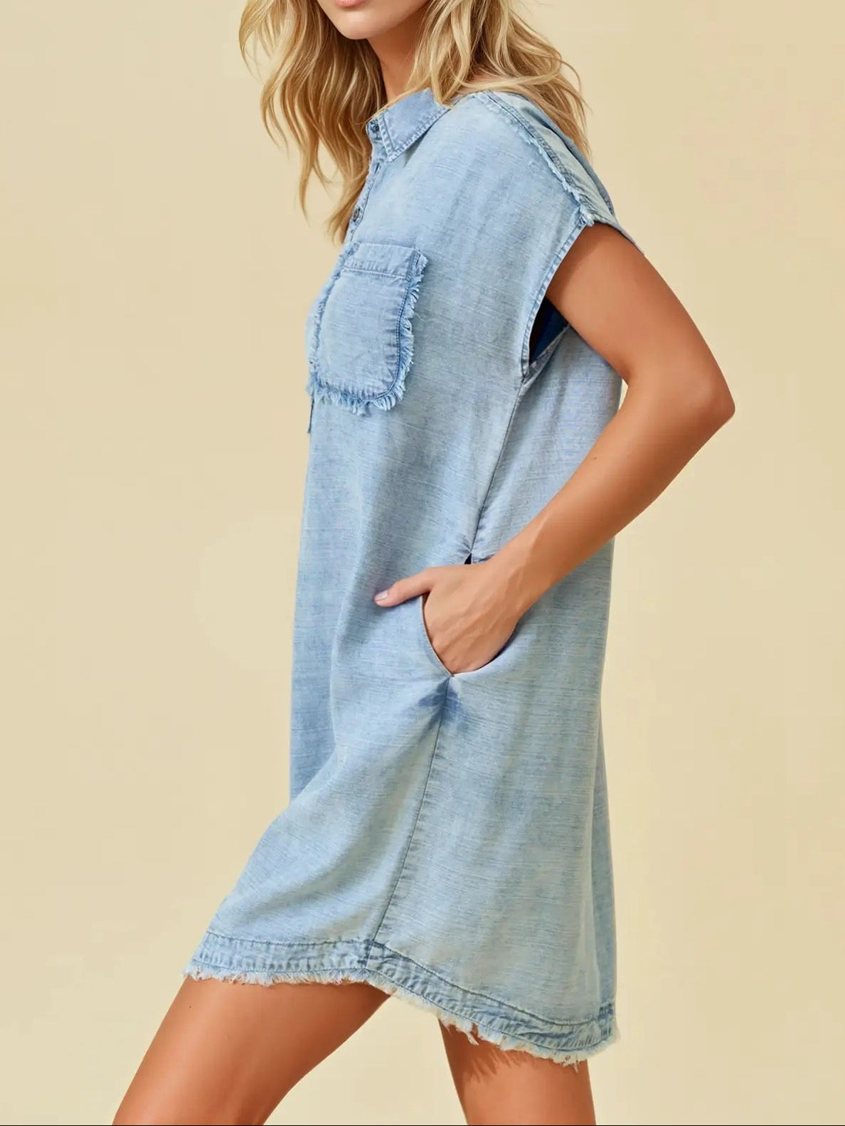 Woman wearing a light blue denim dress against a beige background