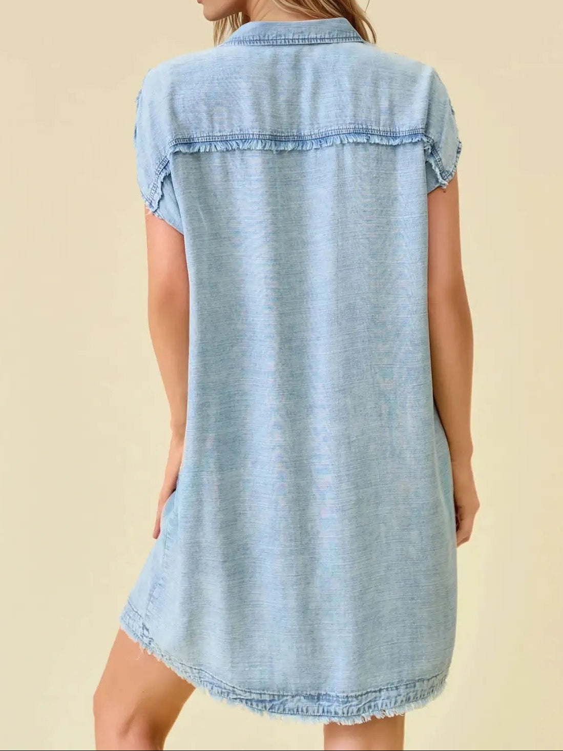 Light blue denim dress worn by a model on a beige background