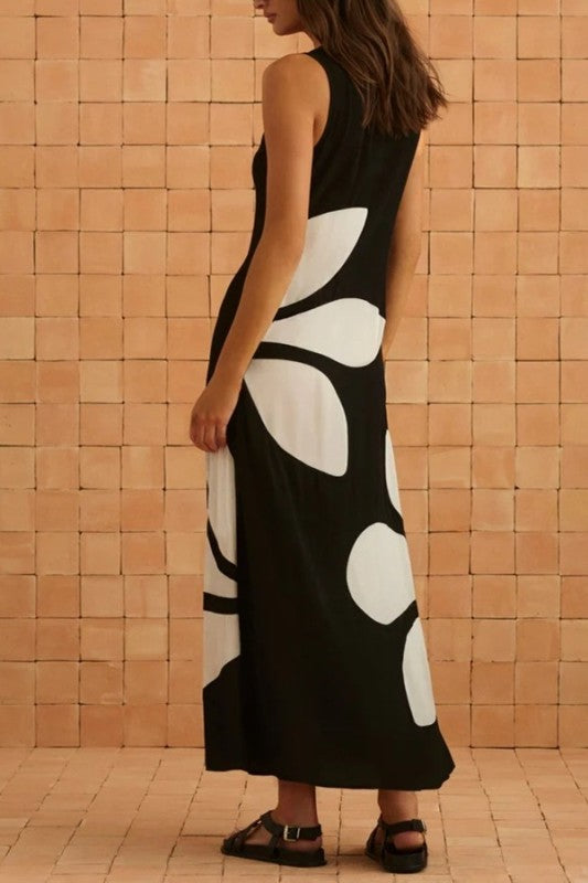 Woman wearing a black dress with white floral patterns against a tiled wall.