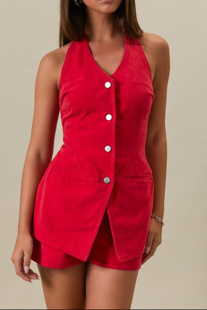 Woman wearing a red sleeveless dress with buttons on a beige background