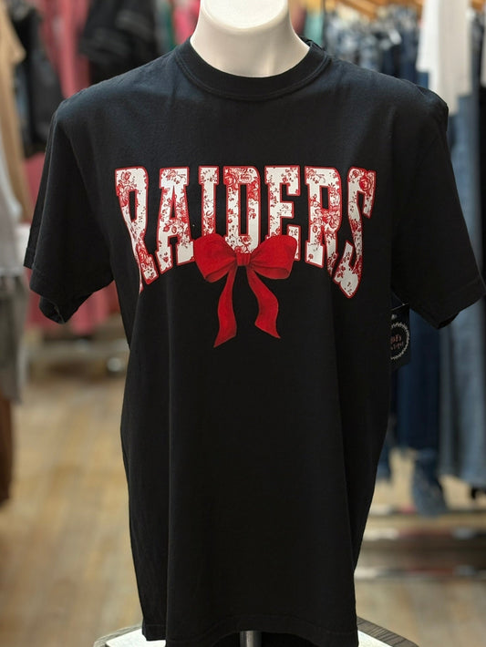 Black t-shirt with 'RAIDERS' and a red bow graphic on a mannequin in a store setting.