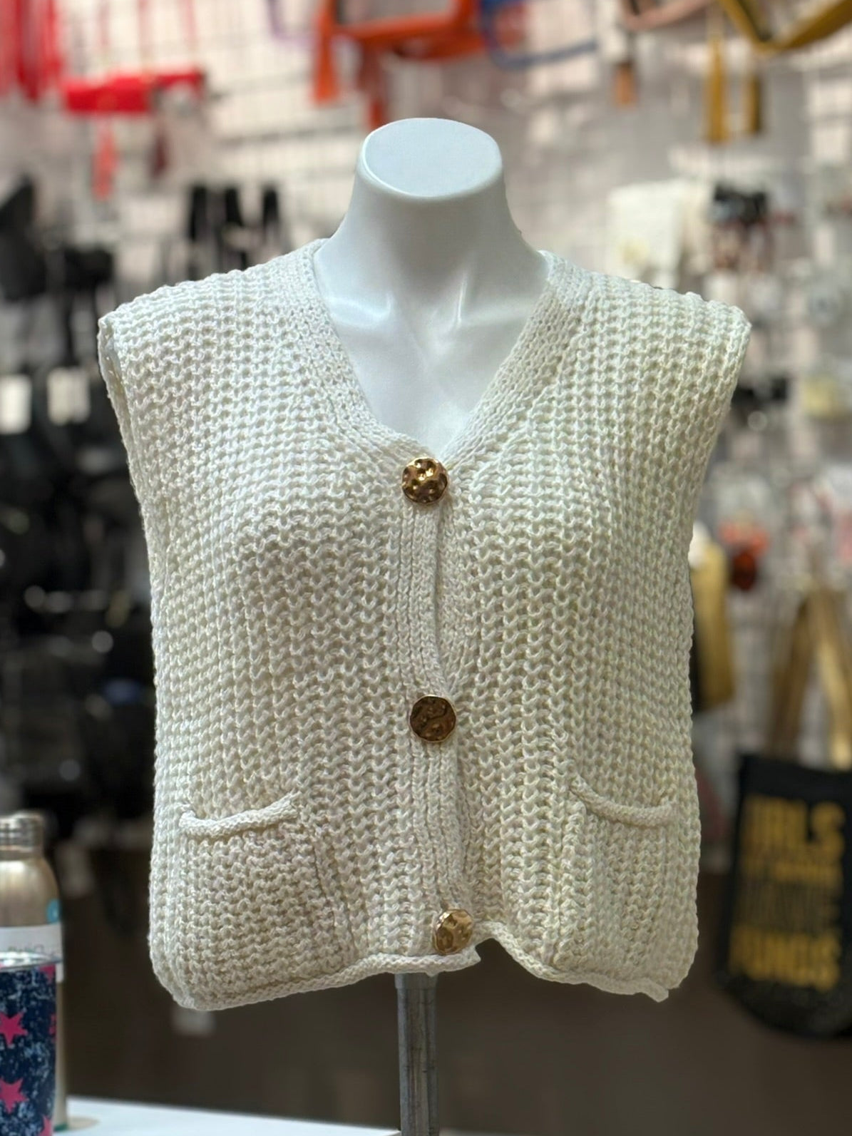 Knitted vest on a mannequin in a store setting with blurred background