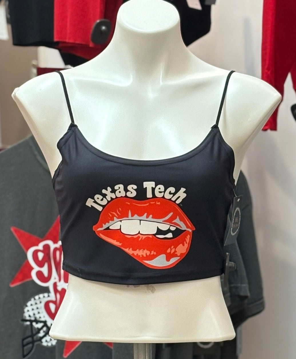 Mannequin wearing a black tank top with 'Texas Tech' and red lip graphic, surrounded by other clothing items.