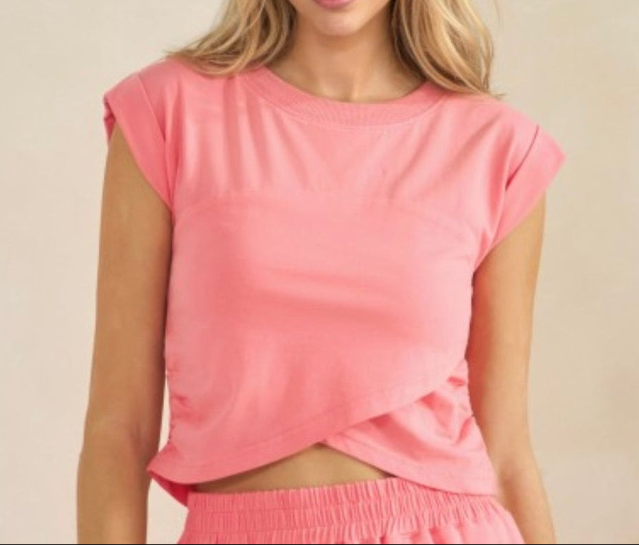 Woman wearing a pink top and shorts against a beige background