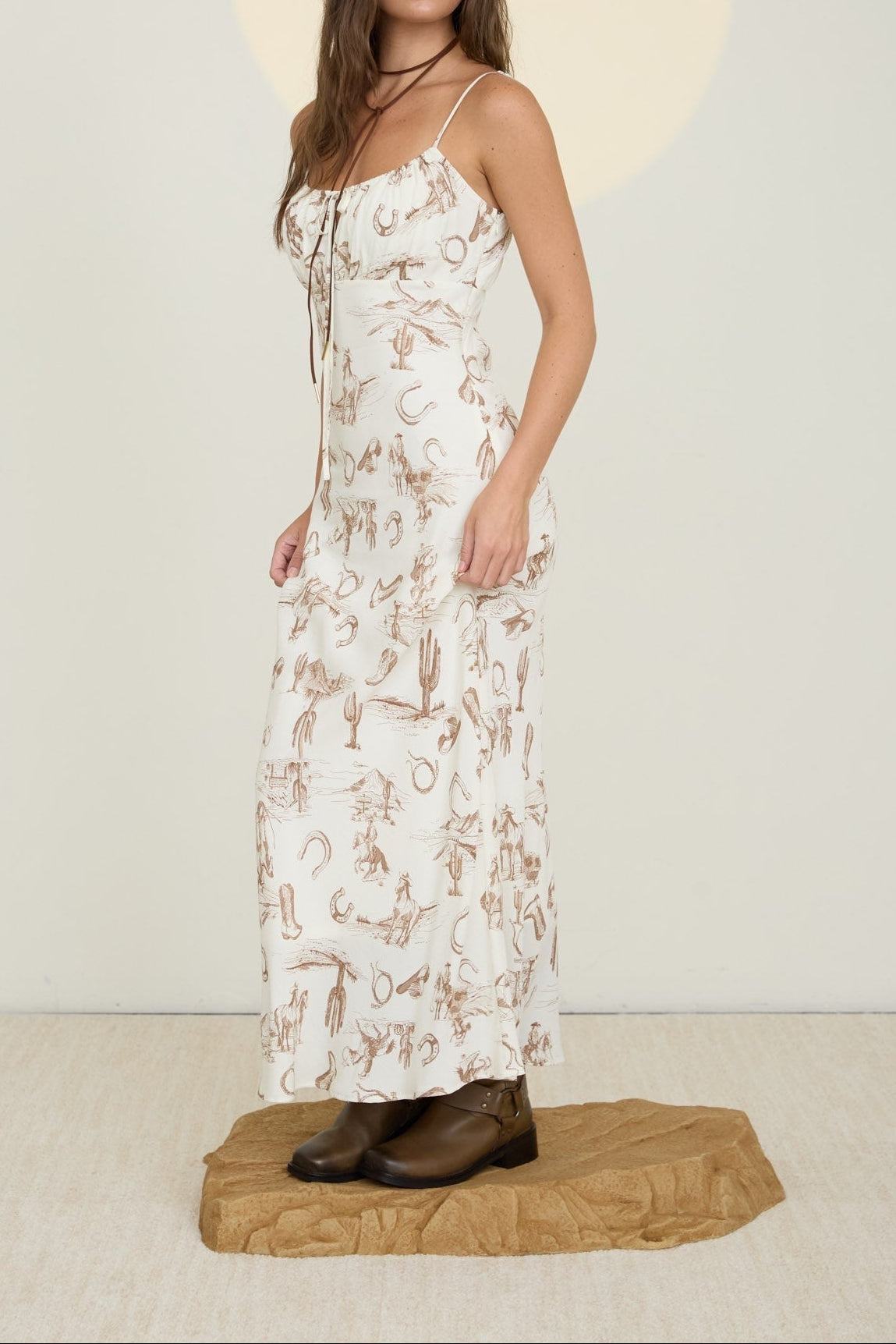 Woman wearing a floral dress standing on a beige platform with a plain background