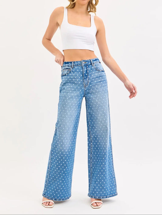 Woman wearing a white tank top and blue polka dot jeans on a white background