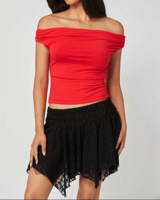 Woman wearing a red off-shoulder top and black skirt on a white background