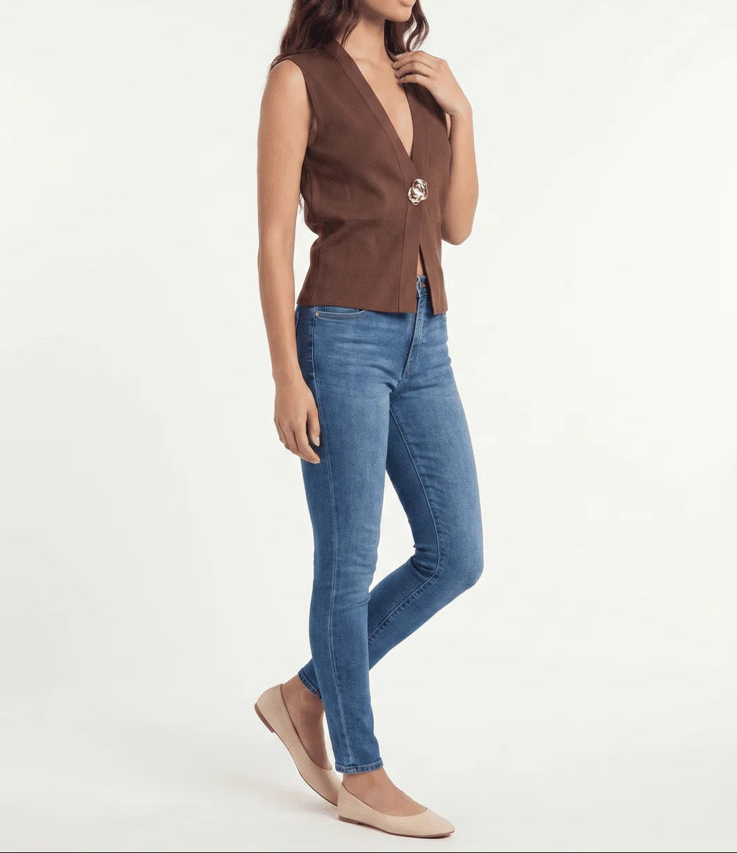 Woman wearing a brown sleeveless top and blue jeans on a white background