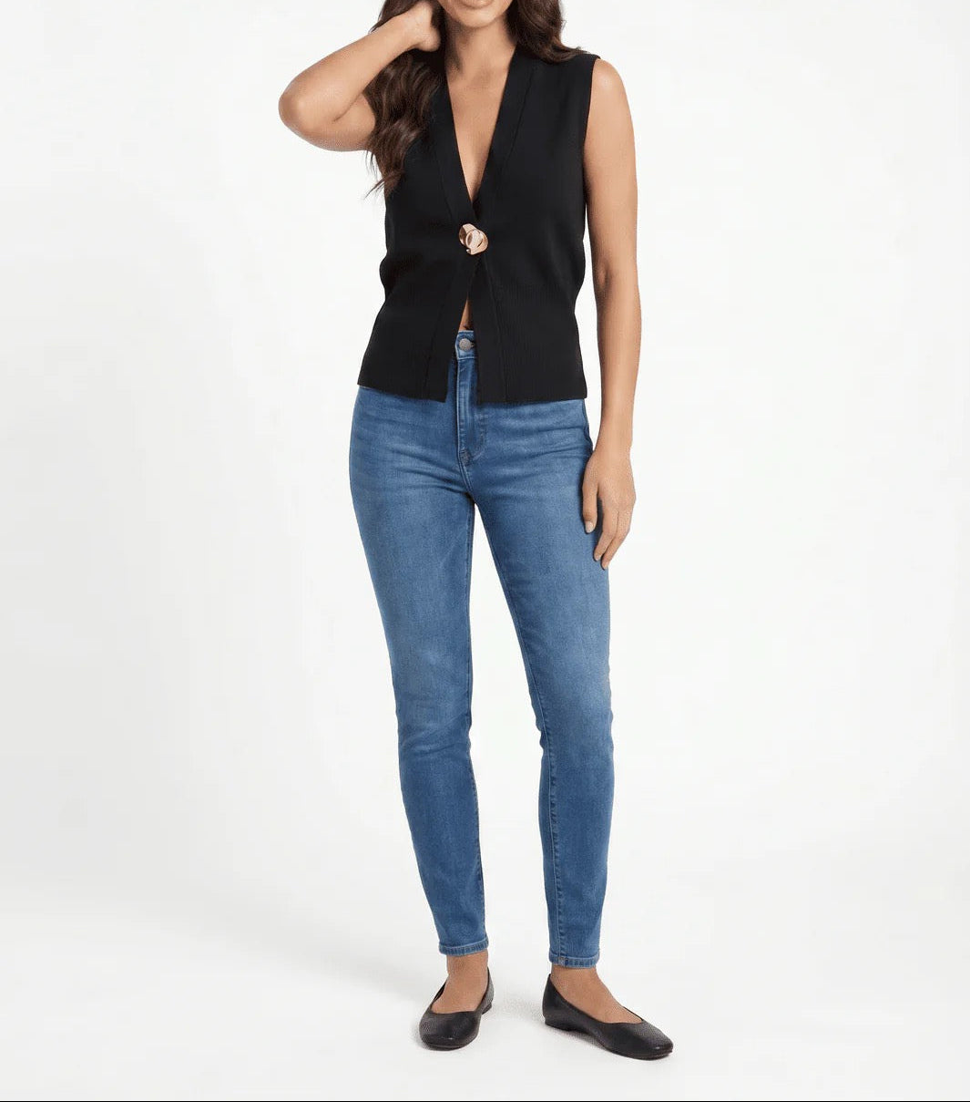 Woman wearing a black sleeveless top and blue jeans on a white background