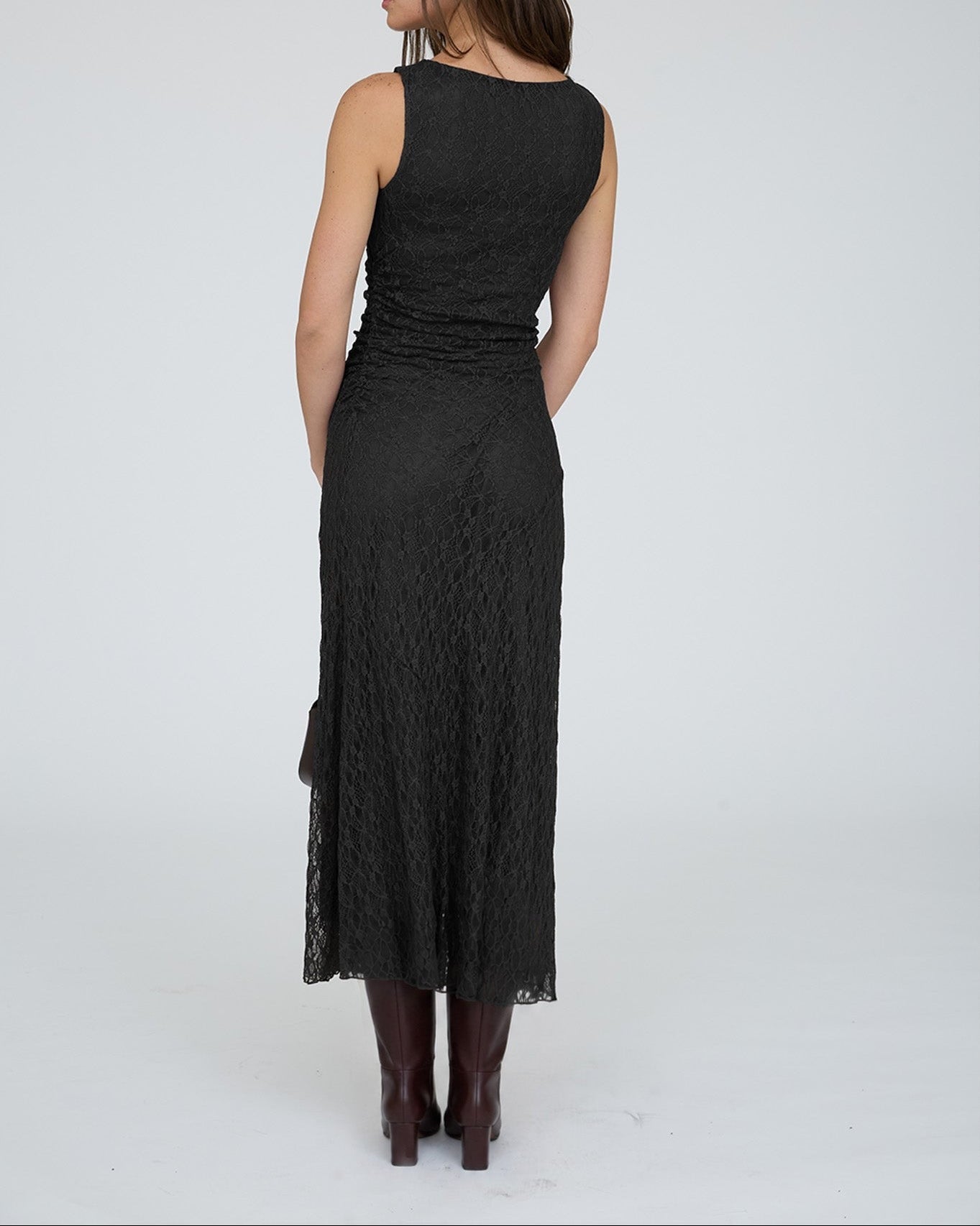 Woman wearing a black sleeveless dress with lace detailing on a white background