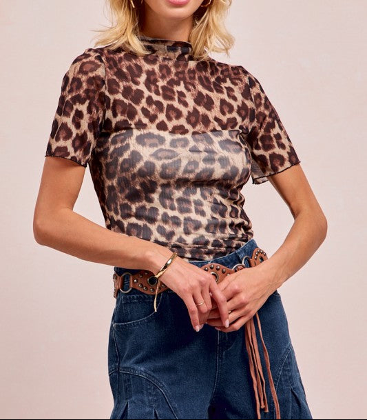 Woman wearing a leopard print top and blue jeans against a plain background