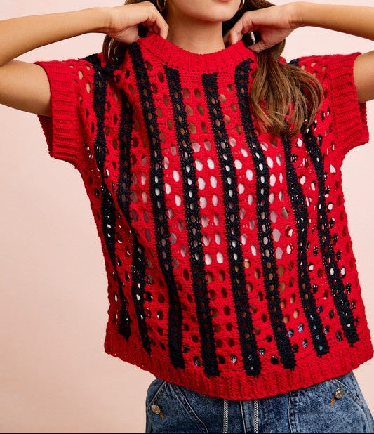 Woman wearing a red crochet top with black and white patterns on a beige background