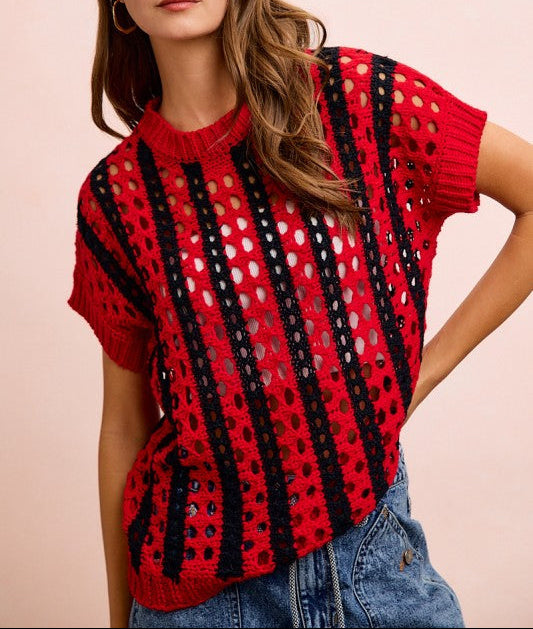 Woman wearing a red and black patterned top against a pink background