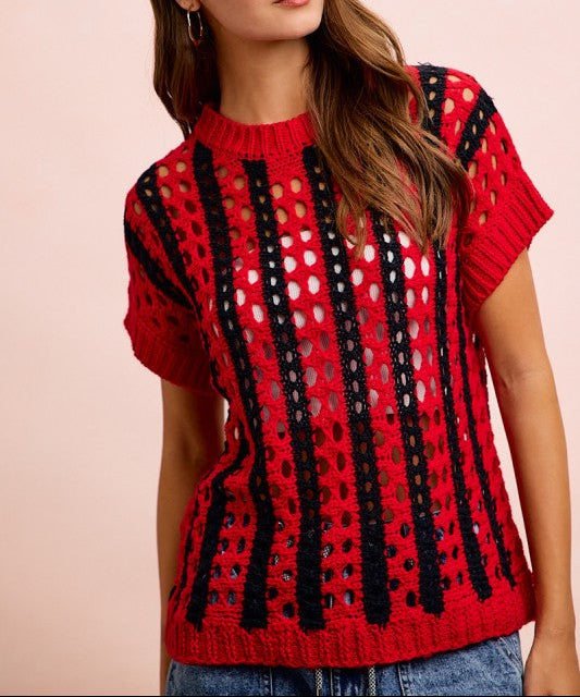 Woman wearing a red and black patterned sweater against a pink background