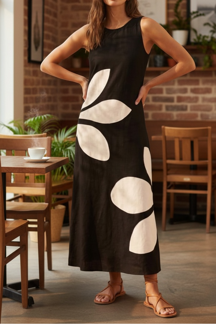 Woman in a black dress with white patterns standing in a casual indoor setting.