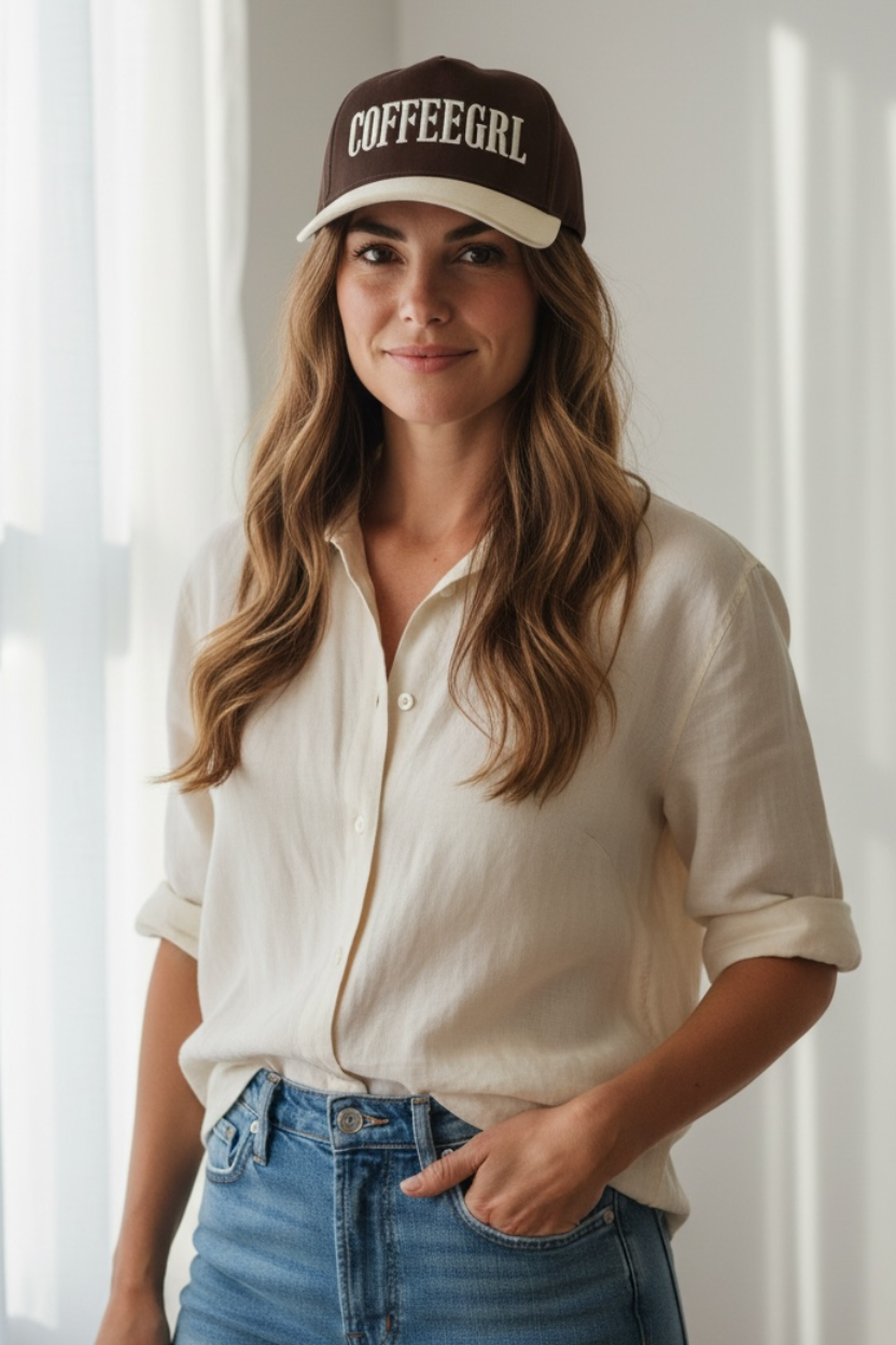 Woman wearing a 'COFFEEGLR' cap in a bright room with sunlight filtering through curtains.
