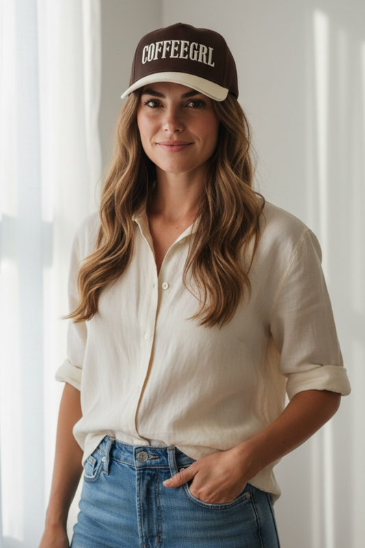 Woman wearing a 'COFFEEGLR' cap in a bright room with sunlight filtering through curtains.